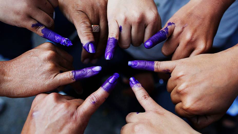 Venezuelanos mostram seus dedos manchados de tinta após votarem para escolha do sucessor de Hugo Chávez, em Caracas