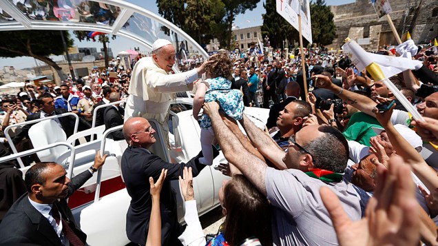 Papa Francisco toca uma criança em meio a multidão de fiéis na Praça da Manjedoura, em Belém, na Cisjordânia