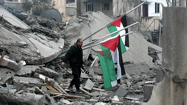Palestino caminha sobre destroços da sede do Hamas, bombardeada por mísseis israelenses
