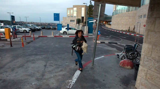 Mulher corre para se proteger após ouvir sirenes de alerta, em Jerusalém