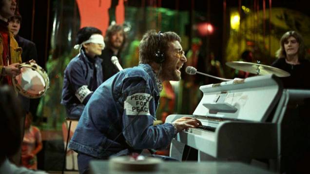 John Lennon e Yoko Ono, ao fundo vendada, participam do programa <em>Top of the Pops</em> em fevereiro de 1970