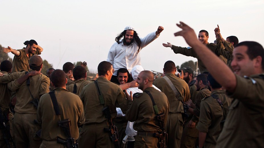 Judeu hassídico membro da seita Breslov, é carregado por um soldado israelense durante uma visita às tropas, perto da fronteira com a Faixa de Gaza