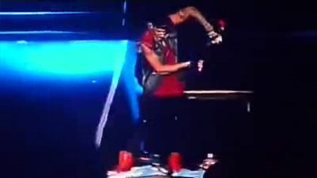 <p>Justin Bieber varre a bandeira argentina do palco, com o microfone</p>