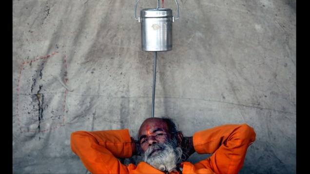 Sadhu, ou homem sagrado hindu descansa próximo às margens do Ganges em Allahabad, Índia