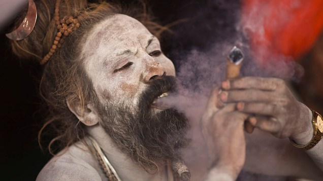 Hindu sagrado fuma às margens do Rio Ganges