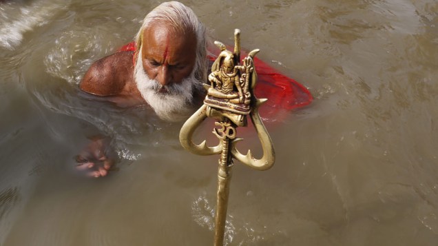 Devoto se banha no Sangam, local de confluência dos rios sagrados Ganges, Yamuna e Saraswatu durante o festival religioso Kumbh Mela na Índia