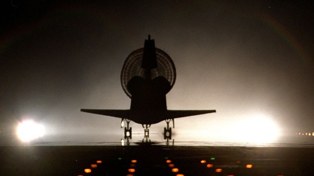 <p>Silhueta do ônibus espacial Discovery durante uma das raras aterrissagens noturnas no Centro Espacial Kennedy, em 6 de junho de 1999</p>