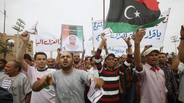 Manifestantes com bandeira da Líbia fazem protesto em Trípoli pedindo que funcionários da era Kadafi sejam banidos. Lei nesse sentido foi aprovada pelo Parlamento