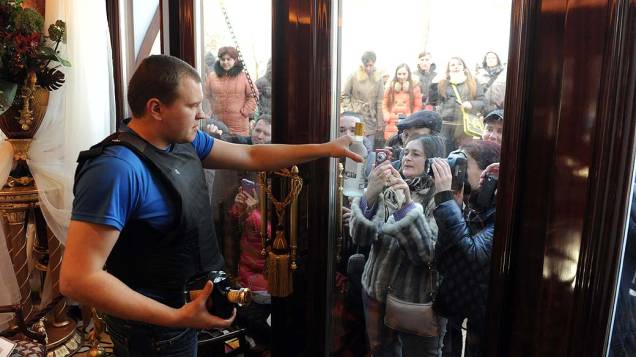 Manifestante que guarda a residência do presidente deposto, mostra uma garrafa de vodca do presidente deposto Viktor Yanukovych foi aberta ao público sábado à noite