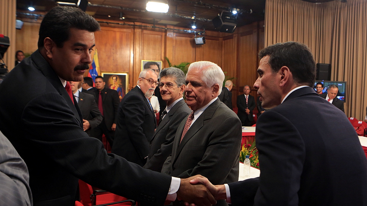 Maduro e Capriles se cumprimentam antes de reunião: após início do encontro, embate entre governo e oposição foi constante