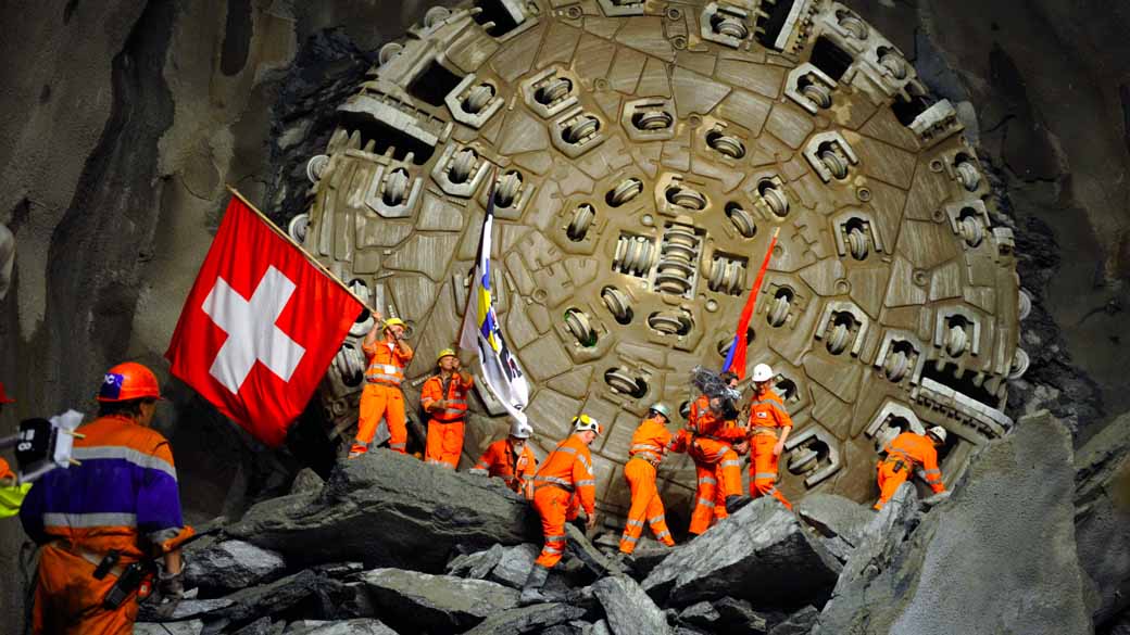 Mineiros celebram após uma furadeira gigante ter concluído o maior túnel do mundo sob os Alpes Suíços