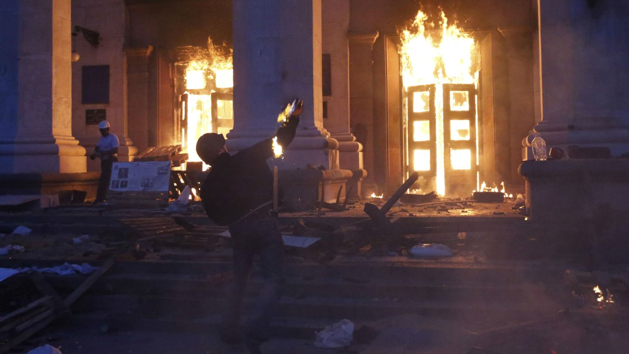 Manifestante lança bomba incendiária contra a entrada do prédio do sindicato de Odessa, ao leste da Ucrânia