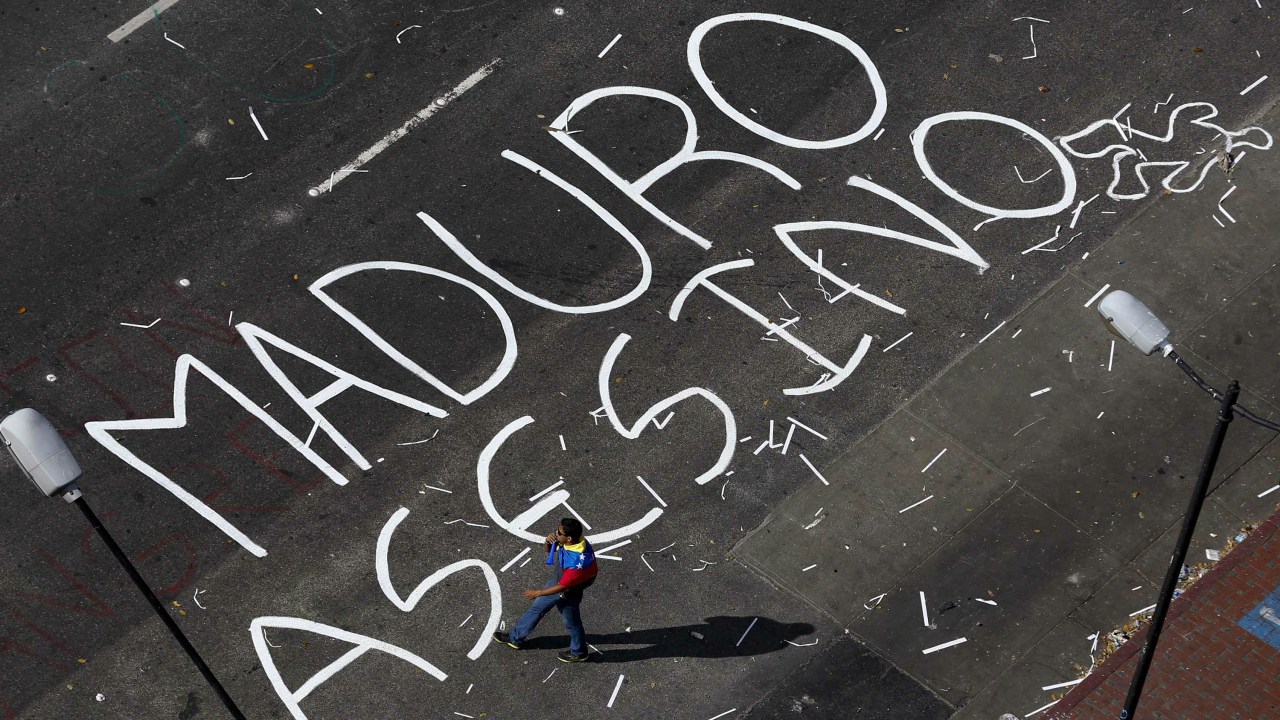 Manifestantes venezuelanos escrevem nas ruas de Caracas em protesto contra o presidente Nicolás Maduro