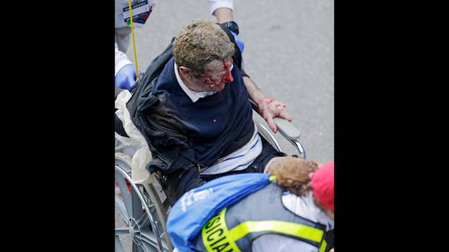 Homem ferido é socorrido por equipes de regaste, após a explosão na maratona de Boston