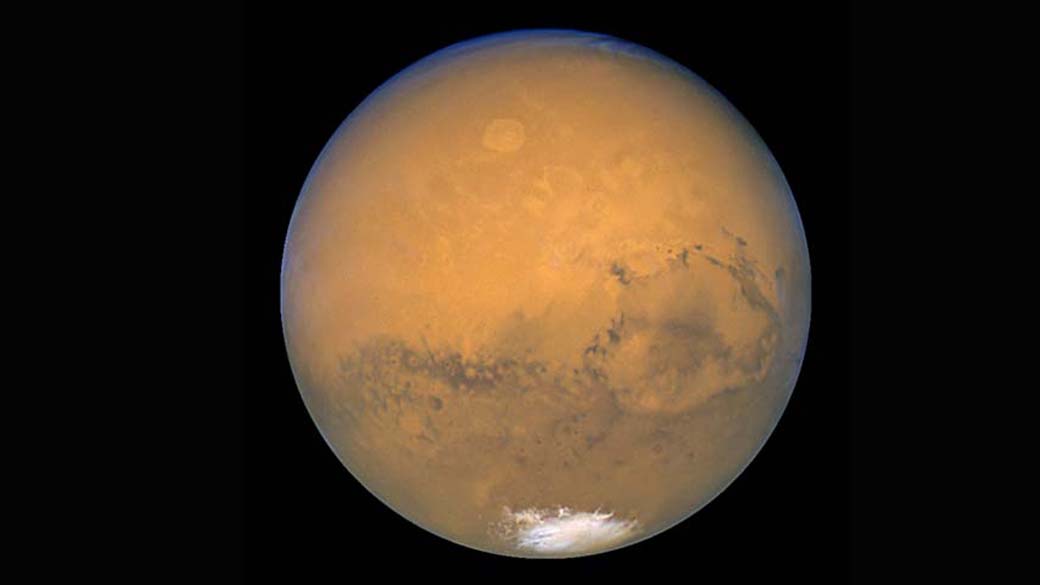 Imagem natural de Marte vista pelas lentes do telescópio Hubble. É possível perceber uma das calotas polares na parte inferior da fotografia - uma mistura de água e dióxido de carbono congelados.