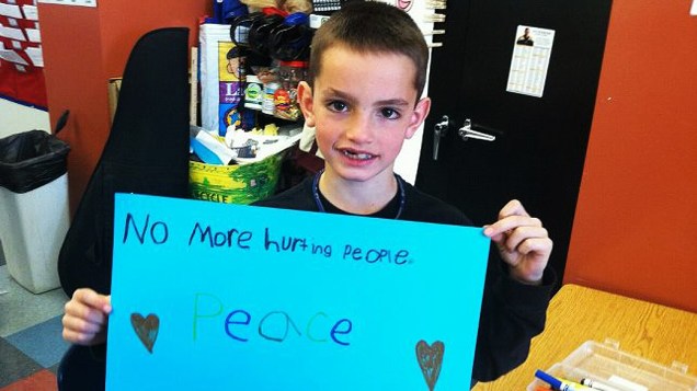 Martin Richard, 8, segura cartaz pedindo paz. O menino é um dos três mortos em atentado, na Maratona de Boston