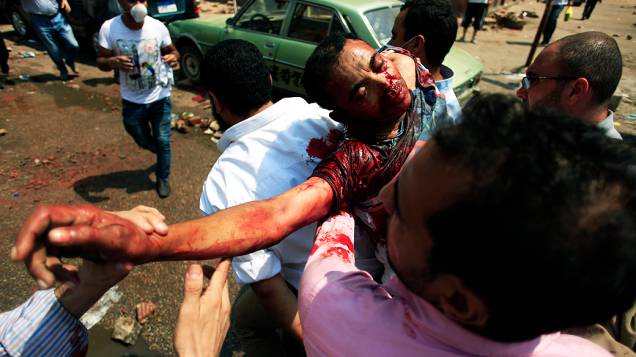 Partidários do presidente deposto do Egito, Mohammed Mursi, carregam um homem ferido pelas forças de segurança egípcias, no Cairo, nesta quarta-feira (14)