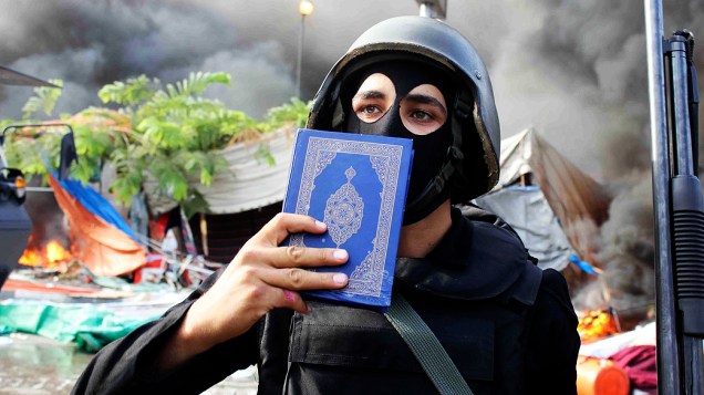 Membro das forças de segurança do Egito segura uma cópia do Alcorão, no Cairo, nesta quarta-feira (14)