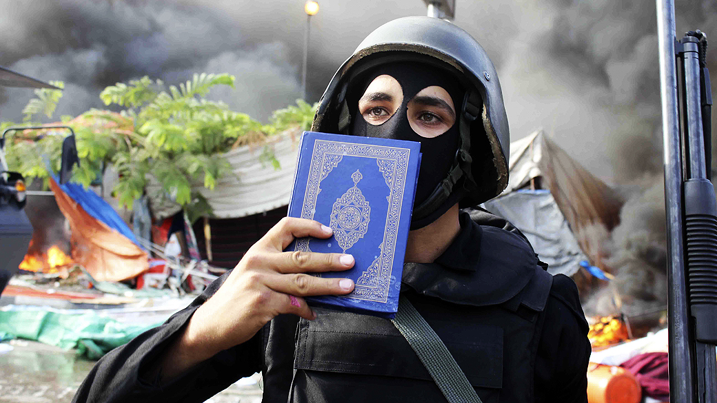 Membro das forças de segurança do Egito segura uma cópia do Corão, no Cairo, nesta quarta-feira (14)