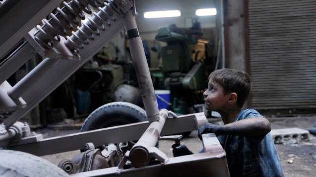 Menino trabalha em fábrica que fornece armamentos para o Exército Livre da Síria, em Alepo