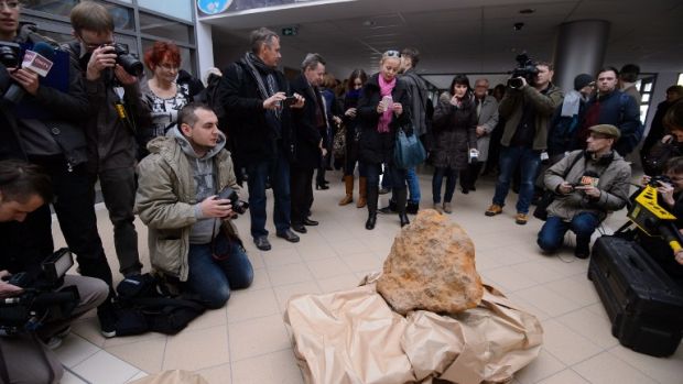 Jornalistas tiram fotos do maior meteorito já encontrado na Polônia, pesando cerca de 300 quilos, em Poznan.