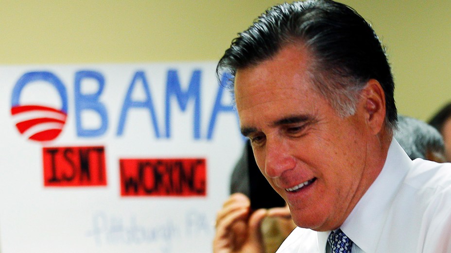 O candidato republicano, Mitt Romney, passa diante de um cartaz com a frase "Obama não está trabalhando", em Green Tree, Pensilvânia