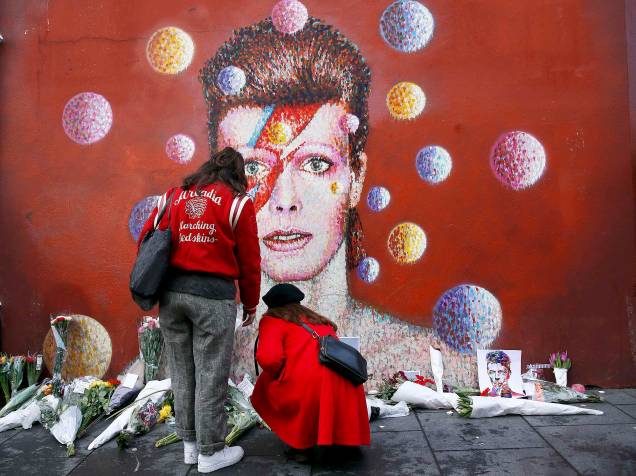 Ingleses deixam flores em frente a uma famosa pintura de David Bowie em Londres, nesta segunda-feira (11)