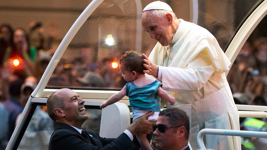 O papa Francisco beija um bebê ao passar de papa-móvel pelas ruas do centro da cidade do Rio, nesta segunda-feira (22)