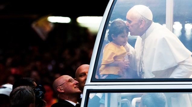 O papa Francisco beija uma criança ao passar de papa-móvel pelas ruas do centro da cidade do Rio, nesta segunda-feira (22)