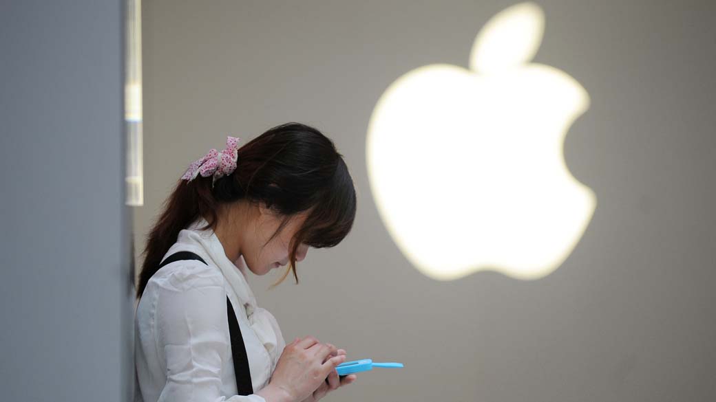 Mulher com celular frente a uma Apple Store