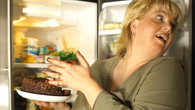 Mulher pegando bolo na geladeira