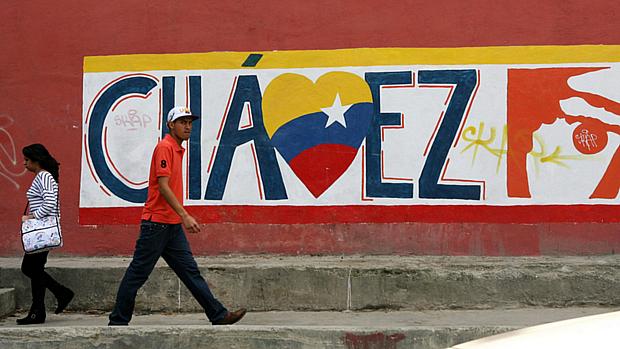 Homem caminha diante de muro que homenageia Chávez em Caracas