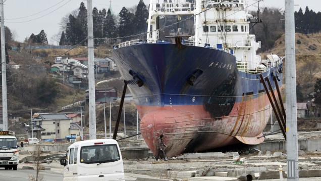 Carros passam ao lado do navio pesqueiro Kyotoku Maru No. 18, encalhado em Kesennuma após o tsunami de 2011