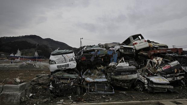 Pilha de carros destruídos pelo tsunami que atingiu o Japão em março de 2011 é vista na cidade de Kesennuma. Ao fundo, o navio Kyotoku Maru No. 18, que entrou aproximadamente 800 metros no município, levado pelas ondas gigantes