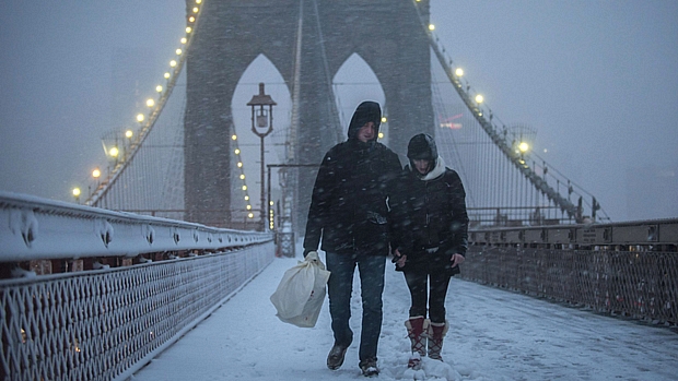 Casal passeia sob a neve na ponte do Brooklyn, em Nova York