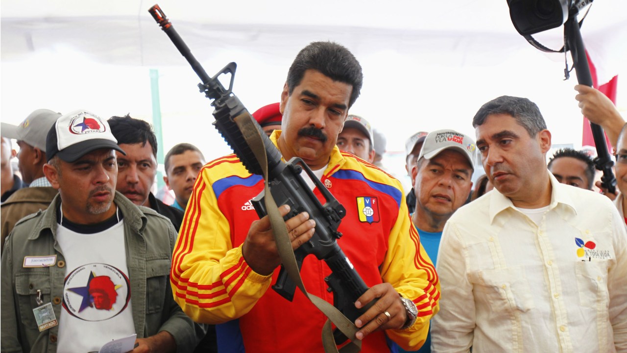 O presidente venezuelano Nicolás Maduro segura uma arma durante ato público em Caracas