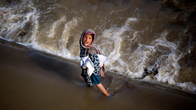 Menina brinca em um riacho na periferia de Cabul, no Afeganistão