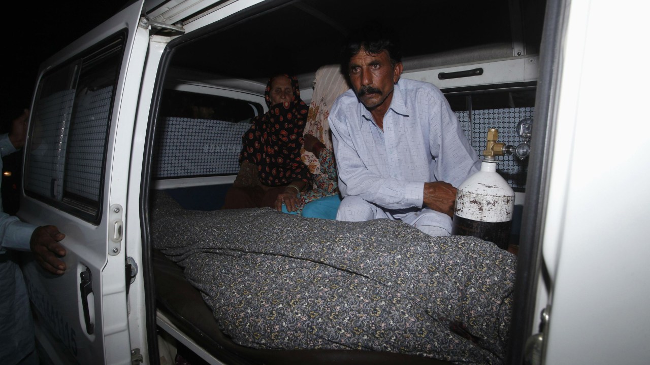 O paquistanês Mohamad Iqbal aguarda ao lado do corpo da mulher Farzana Parveen, apedrejada até a morte pela própria família