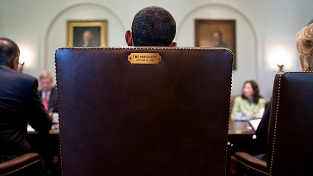 Obama sentado na cadeira presidencial
