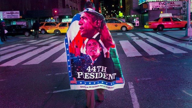 Eleitor na Times Square em Nova York enrolado em uma bandeira de Barack Obama