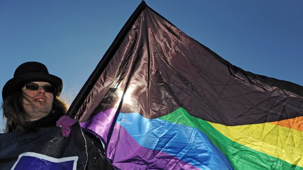 Um homem segura uma bandeira do orgulho LGBT no centro de Moscou, para comemorar o Dia Internacional da Mulher