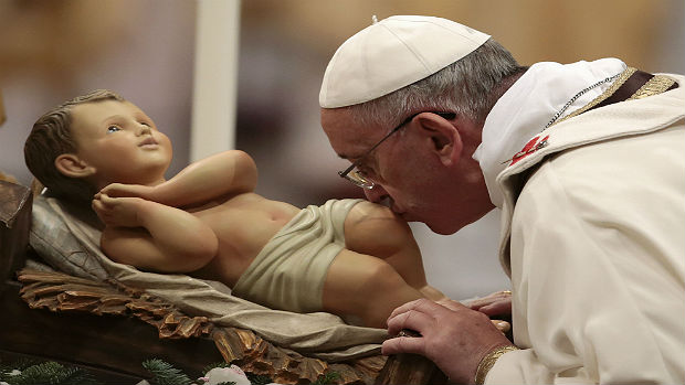 O papa Francisco beija a imagem do menino Jesus durante a missa da noite de Natal na Basílica de São Pedro, no Vaticano