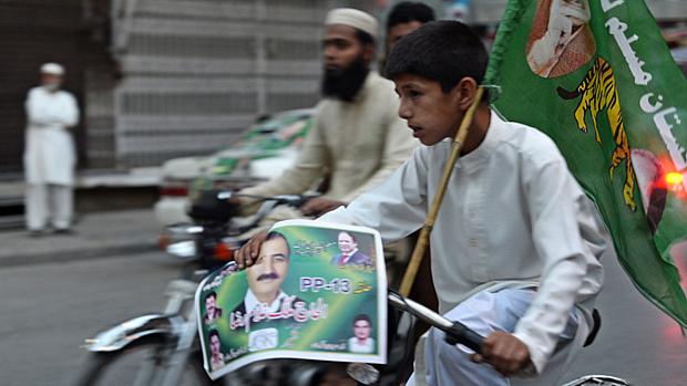 Menino faz campanha para candidato de eleições legislativas na cidade de Rawalpindi, no Paquistão