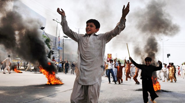 Crianças brincam em meio às barricadas de fogo durante protesto de muçulmanos em Rawalpindi, no Paquistão, em protesto contra o filme anti-islâmico