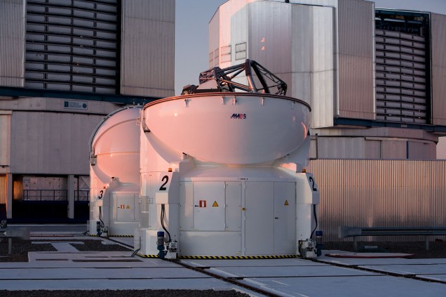 <p>A imagem mostra dois dos telescópios auxiliares do VLT em frente a duas unidades principais, na plataforma de observação do Observatório do Paranal, Chile.</p>