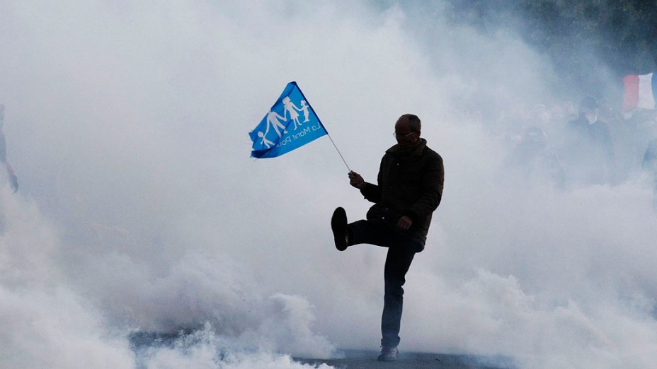 Nuvens de gás lacrimogêneo cercam um homem durante confrontos no final de uma marcha de protesto chamado "La Manif pour tous" (Demonstração para Todos) contra a legalização do casamento homossexual em Paris, na França