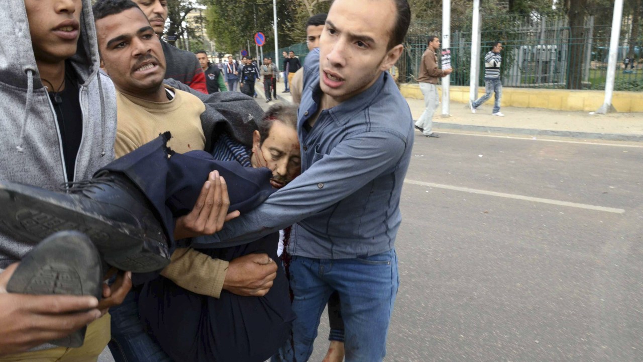 Pessoas carregam o corpo de um chefe de polícia morto após a explosão de duas bombas nas imediações da Universidade do Cairo, no Egito