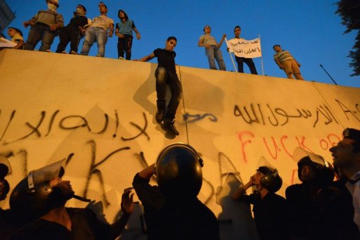 Manifestantes descem de muros da embaixada americana no Cairo observados por policiais em protesto em 11 de setembro