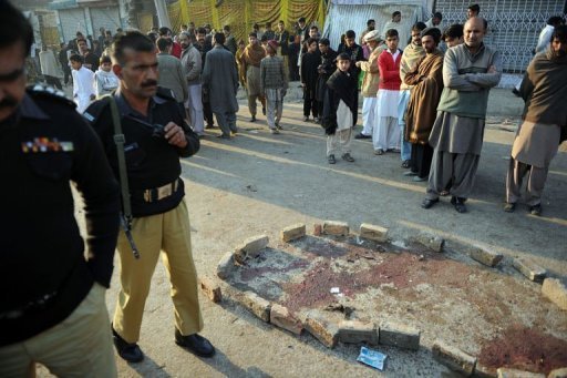 Policiais paquistaneses e moradores observam área de atentado suicida durante procissão xiita em Rawalpindi