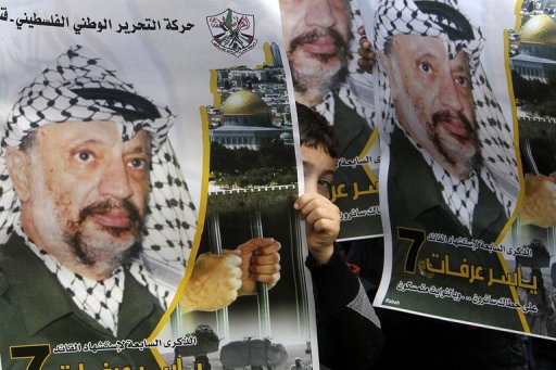 Menino segura um pôster com a foto do ex-lider palestino Yasser Arafat em 11 de novembro em Nablus